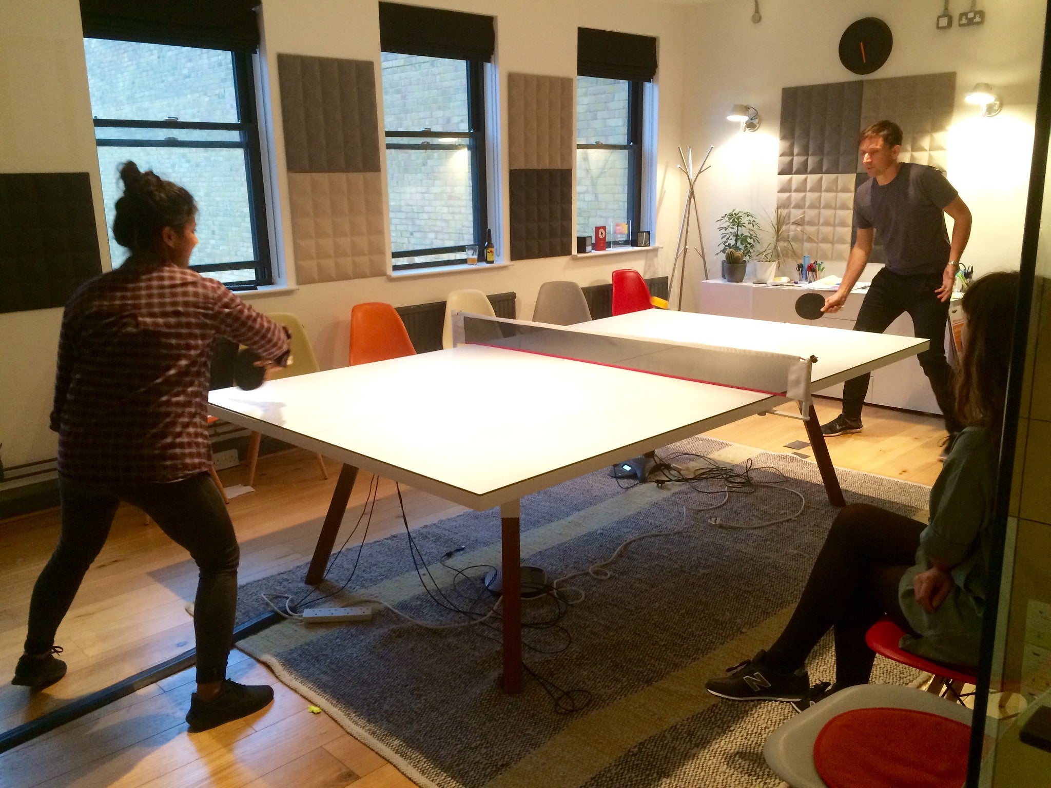 A man and woman playing a game of table tennis indoors.